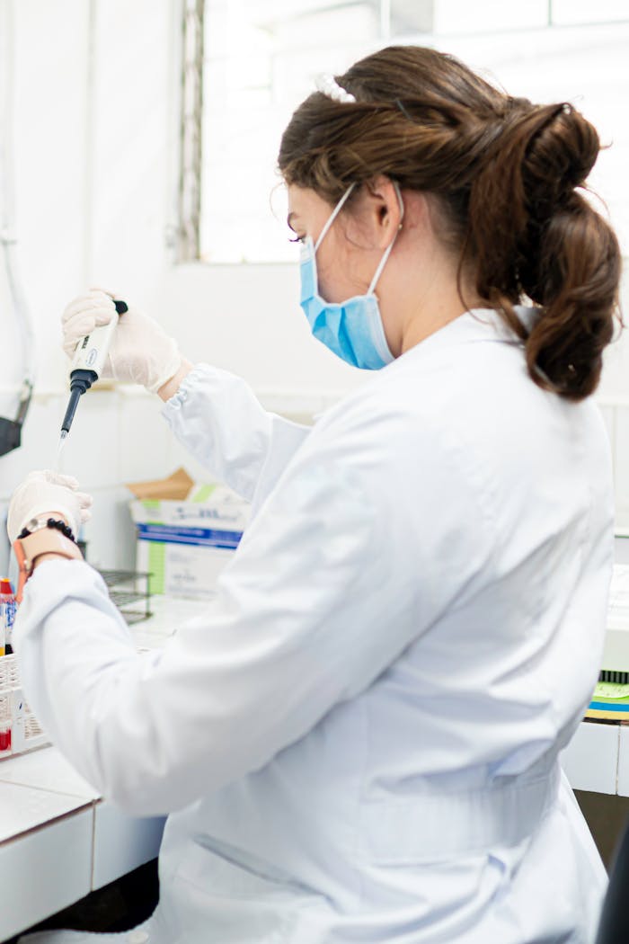 why-choose-us Woman scientist in lab coat performing tests with pipette in a laboratory setting.