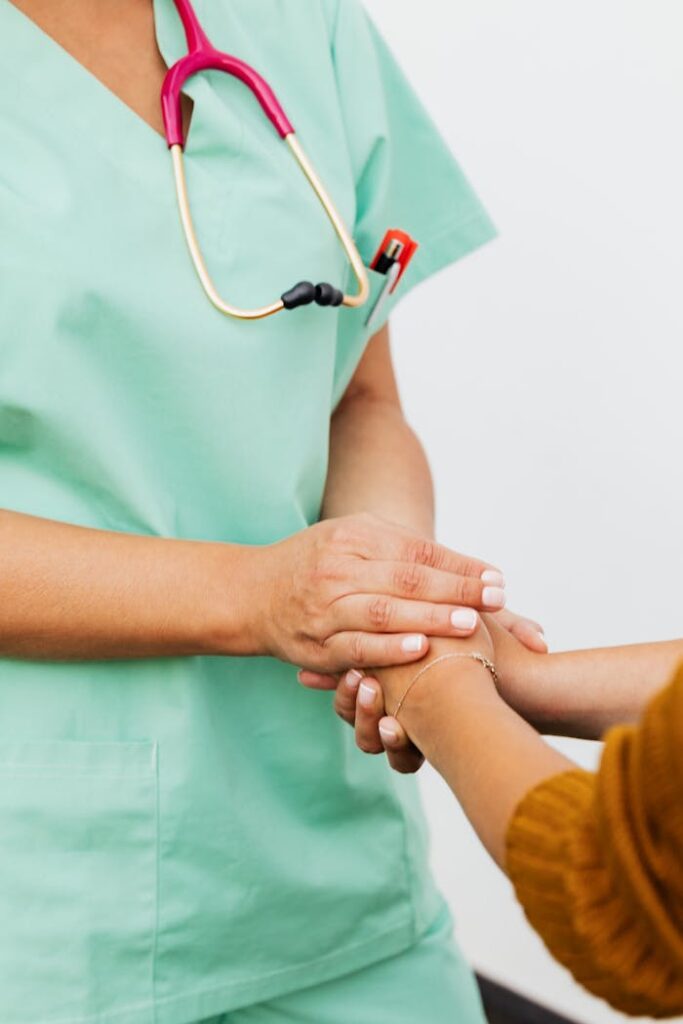 pexels photo 5207015 A nurse in green scrubs gently clasps a patient's hand, offering support.