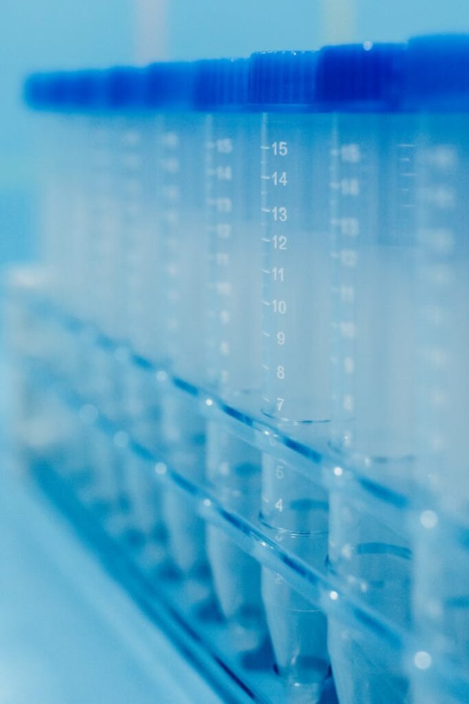 pexels photo 7722525 Vertical shot of clear plastic test tubes in a rack with blue caps in a laboratory setting.